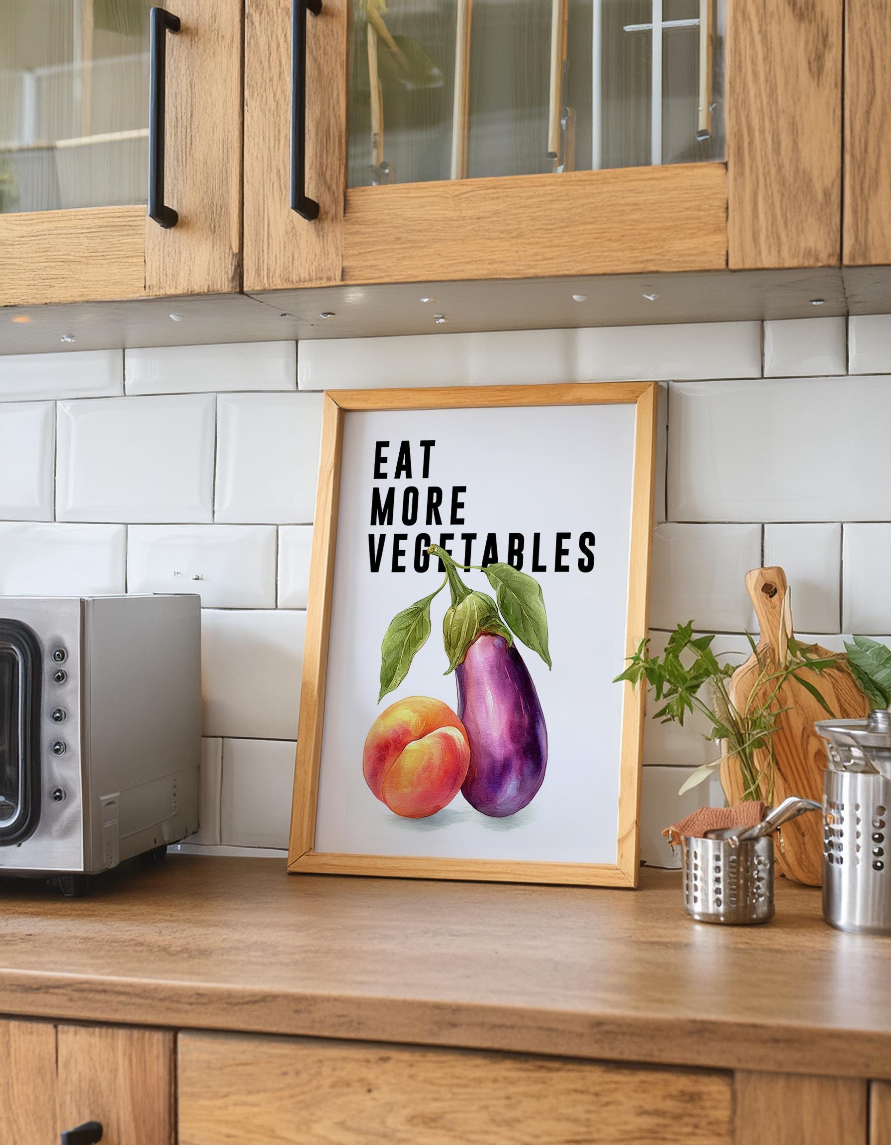 Playful food-themed wall art featuring bold black typography reading “Eat More Vegetable” above a colourful illustration of an aubergine and peach. Modern humorous kitchen poster with a cheeky twist, perfect for kitchens, dining rooms, or as a fun gift for friends. Printed to order on premium satin photo paper by Hues & Reflections UK.