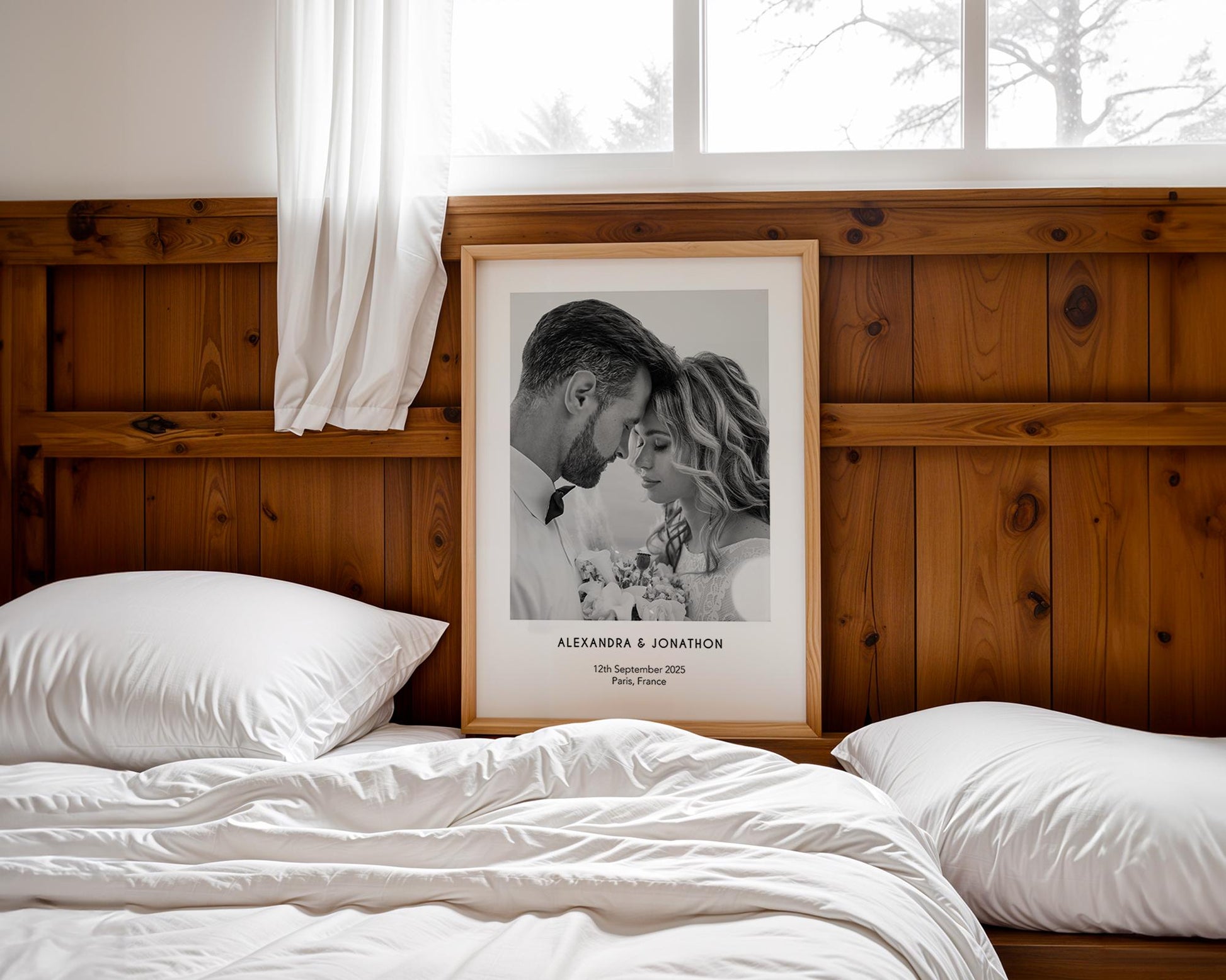A personalised wedding photo print featuring a couple on their wedding day in elegant natural light. The bride wears an off-shoulder white gown and holds a soft green and white bouquet while the groom embraces her. Minimal modern layout with names, wedding date and venue below the image. A stylish custom keepsake for couples, weddings, anniversaries or home decor.