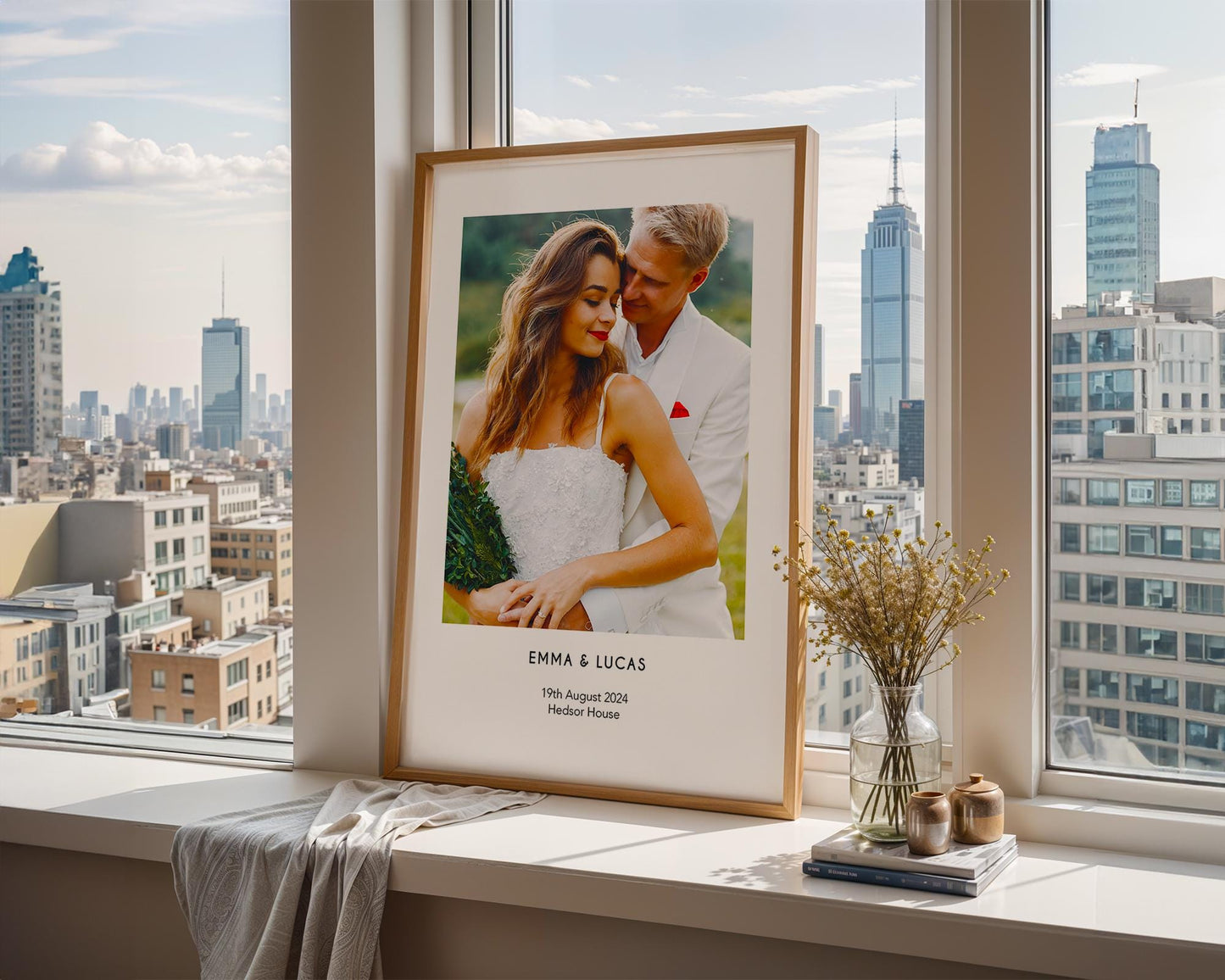 A personalised wedding photo print featuring a couple on their wedding day in elegant natural light. The bride wears an off-shoulder white gown and holds a soft green and white bouquet while the groom embraces her. Minimal modern layout with names, wedding date and venue below the image. A stylish custom keepsake for couples, weddings, anniversaries or home decor.