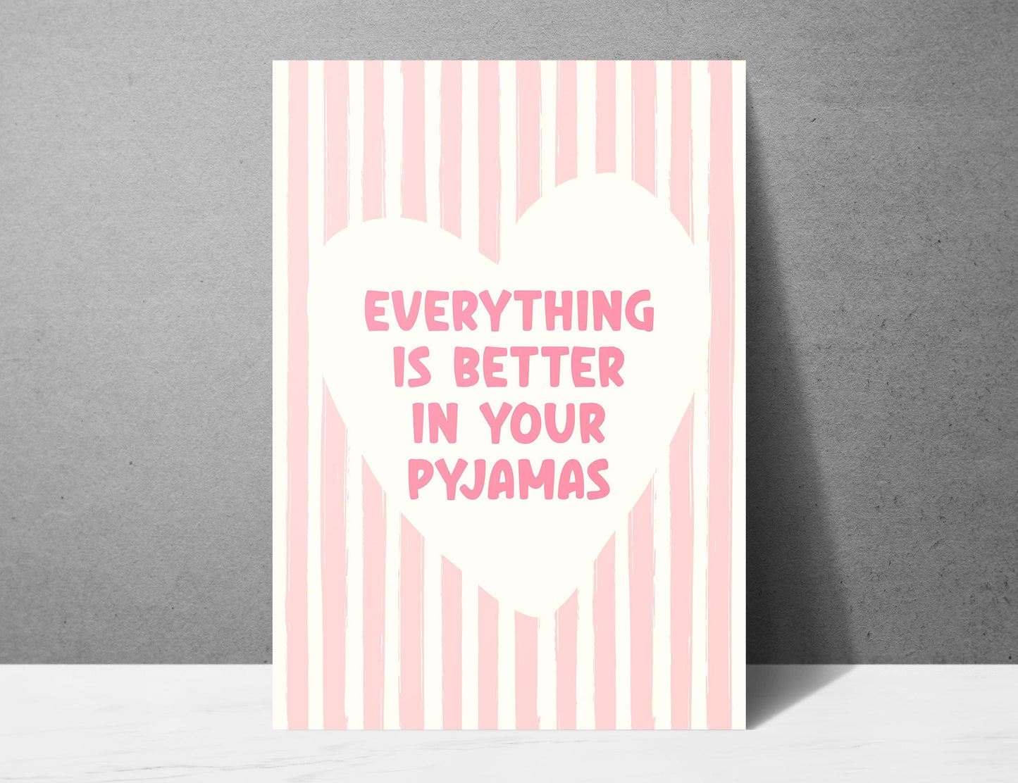 Everything Is Better In Your Pyjamas print, funny pink bedroom wall art featuring a chunky hand drawn quote inside a cream heart on a pink hand painted stripe background, cute cosy bedroom decor poster for above the bed dressing rooms walk in wardrobes and girly interior schemes, perfect thoughtful gift for best friends sisters bridesmaids hen dos Galentines Mother's Day and housewarming, printed on premium 260gsm satin lustre paper, handmade in the UK by Hues and Reflections small business